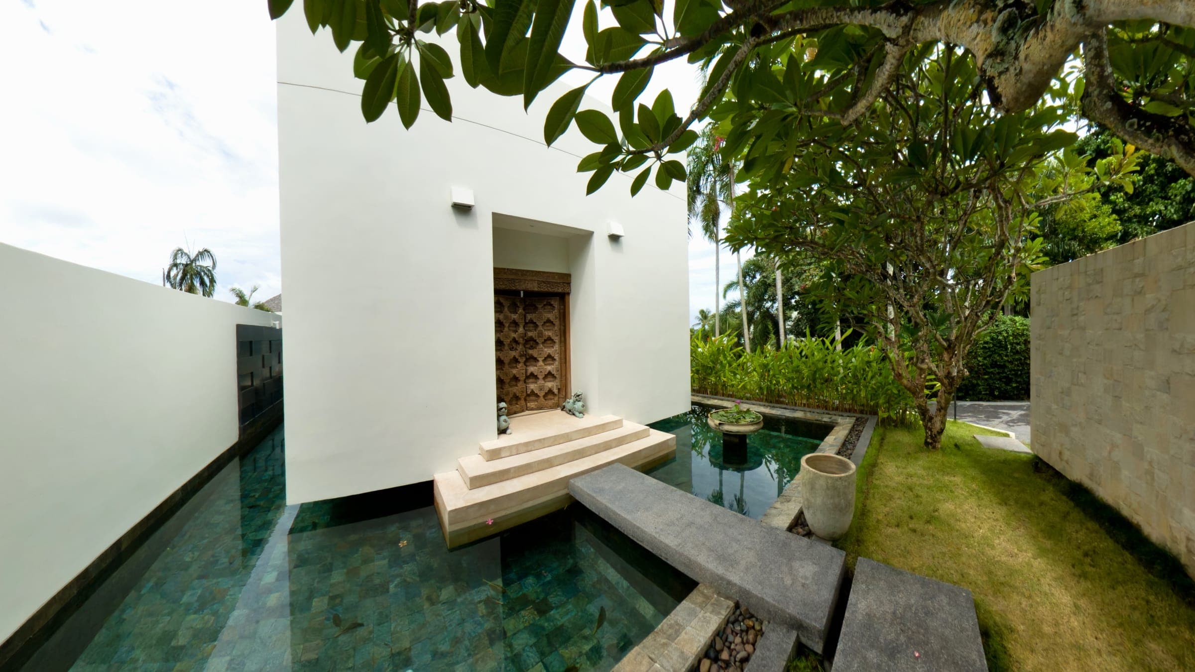 Villa entrance with carved wooden door and koi pond